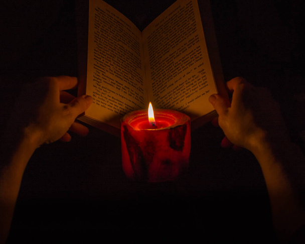 Reading a book by candlelight - Фото, изображение