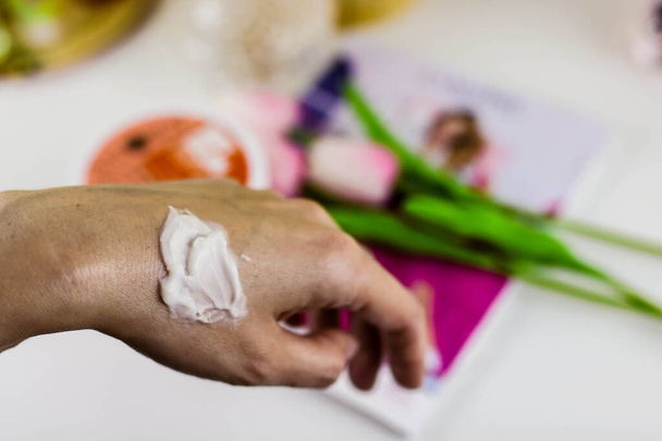 Frau befeuchtet ihre Hand mit kosmetischer Creme - Foto, Bild
