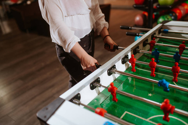 Close up of hands of a caucasian woman in a white shirt while playing table football. Fun time - Foto, Bild