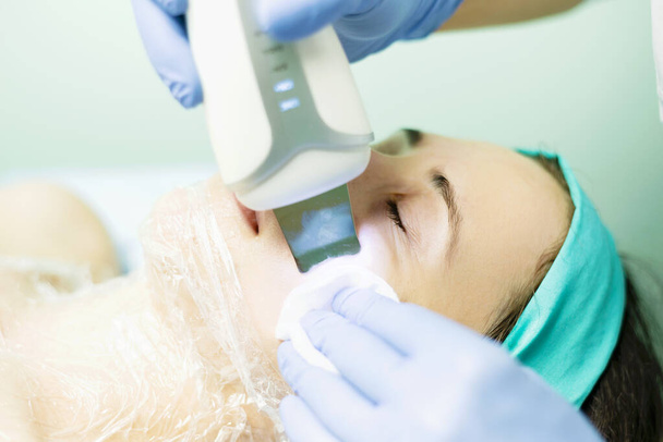 Foto de mujer limpiando la piel facial con dispositivo ultrasónico, concepto de salud y belleza
. - Foto, Imagen