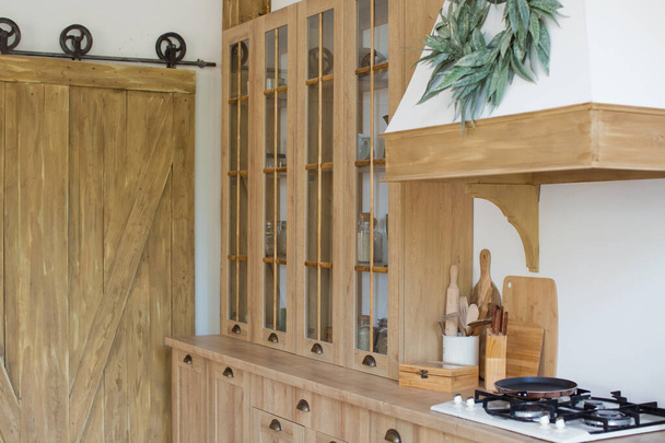 Interior de cocina de madera clara con utensilios de cocina en los estantes y en la pared. Hermoso diseño interior de cocina - Foto, Imagen