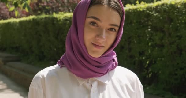 Gyönyörű fiatal nő a kamerába néz, hagyományos fejkendőt visel. Vonzó nő a hidzsáb - Felvétel, videó