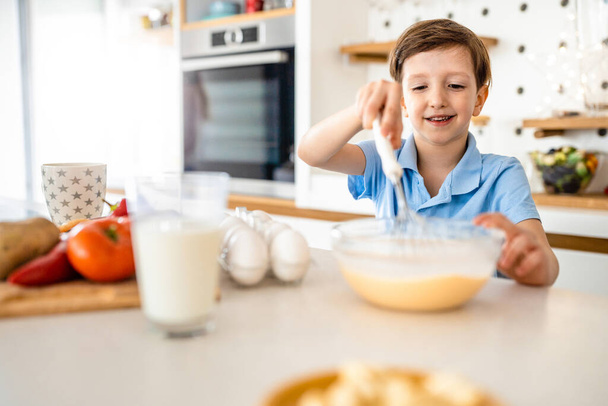 Happy beautiful child boy preparing breakfast at home kitchen - Fotó, kép