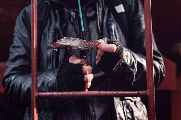 Drogadicto fumando opio en papel de aluminio, alias persiguiendo al dragón, cerca de las manos con enfoque selectivo
 - Foto, Imagen