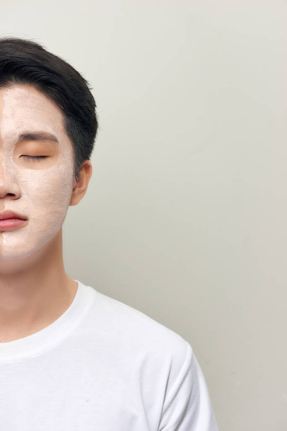 Handsome man with clay mask on his face against white background - Fotó, kép