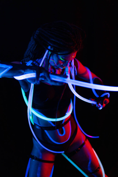 Portrait of a Warror Girl with Glowing Tubes in Neon UF Light (англійською). Model Girl with Dreadlocks and Fluorescent Creative Psychedelic MakeUp, Art Design of Female Disco Dancer Model in UV, Colorful Abstract - Фото, зображення