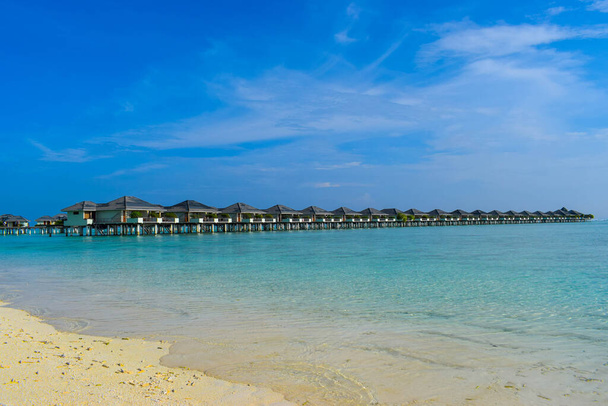 Napfényes strand fehér homokkal, kókuszpálmafákkal és türkiz tengerrel. Nyári vakáció és trópusi strand koncepció. Tengerentúli Maldive Island üdülőhely. - Fotó, kép
