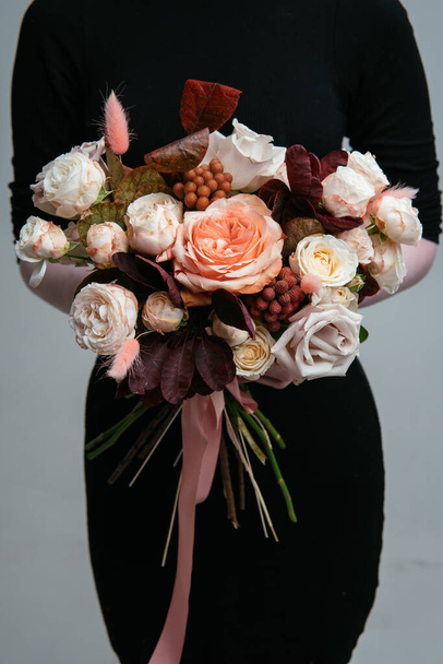Bouquet of flowers in the hands of a woman florist on a light background. Rosa, cotinus, brunia, lagurus. - Zdjęcie, obraz