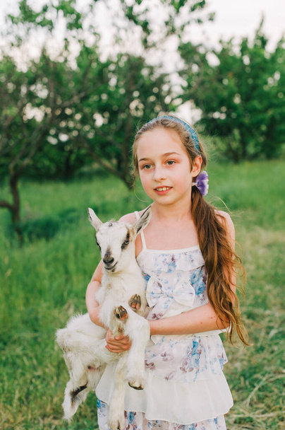 Dziewczyna z kozłem na farmie. Miłość i troska. Wiejskie zwierzęta. szczęśliwe dziecko przytula kozę, koncepcję jedności natury i człowieka. Przyjaźń dzieci i zwierząt. Szczęśliwego dzieciństwa. Dziewczyna i koza - Zdjęcie, obraz