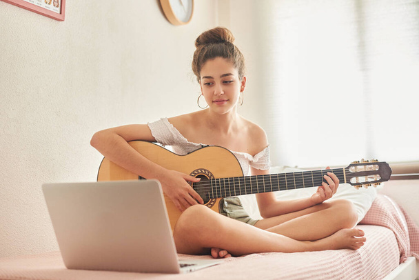 Mädchen lernt Gitarre online mit Laptop - Foto, Bild
