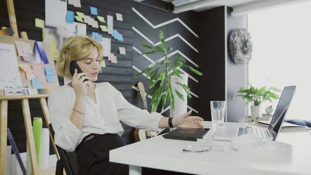 Ξανθιά κοντή επιχειρηματίας που μιλάει στο τηλέφωνο στο γραφείο - Φωτογραφία, εικόνα