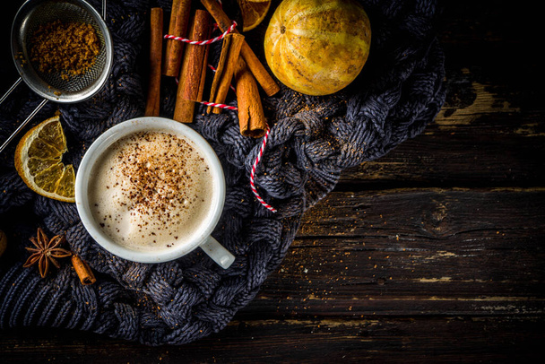 Herfst zoete warme drank, Chai Buttered Rum, Pompoen taart of Pompoen Spice Coffee Latte. Gezellige herfst achtergrond met traditionele latte cup, kruiden en oude trui, op rustieke houten achtergrond - Foto, afbeelding