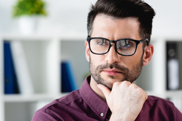 confident, pensive businessman in eyeglasses touching chin while looking away - Фото, изображение