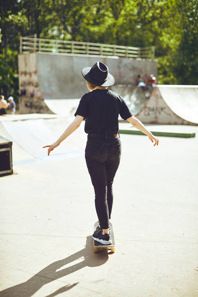 Young teenage girl in hat rides a skateboard in a skatepark in a black clothes, active and sport lifestyle - Fotografie, Obrázek