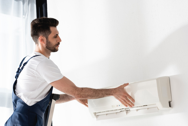 young repairman opening air conditioner fixed on while wall - Photo, Image
