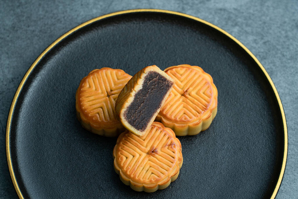 Měsíční koláčky pro Mid-Autumn Festival jsou umístěny na černém talíři se zlatým lemem - Fotografie, Obrázek