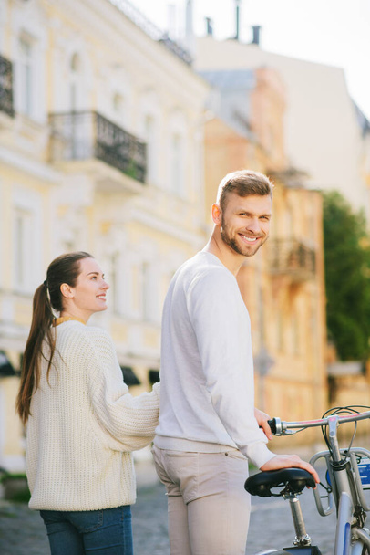 Smiling man with bicycle and woman looking at him - Фото, зображення