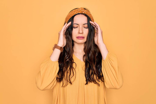 Mladá krásná žena na sobě ležérní tričko a diadém stojí nad žlutým pozadím s rukou na hlavě pro bolest hlavy, protože stres. Trpící migréna. - Fotografie, Obrázek