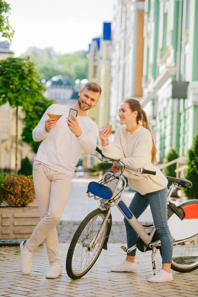 Man taking selfie on smartphone with woman on bicycle. - Фото, зображення