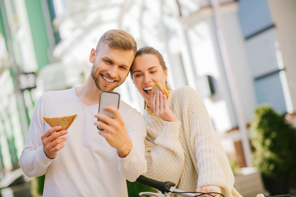 Cheerful man and woman taking selfie on smartphone - Fotó, kép