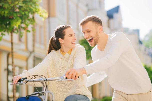 Man teaching a joyful woman riding bike - Foto, afbeelding