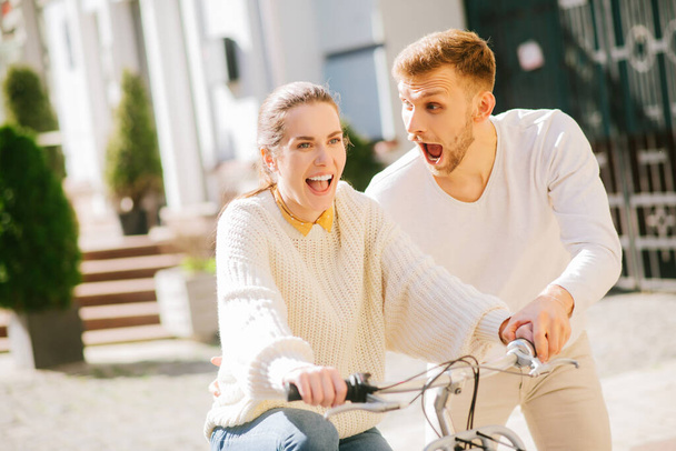 Enthousiaste vrouw op de fiets en een man die haar steunt - Foto, afbeelding