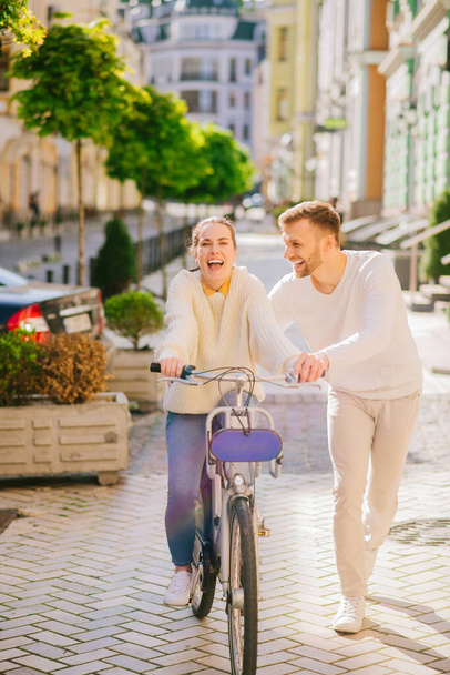 Happy young woman on bicycle and man running nearby - Foto, Imagem