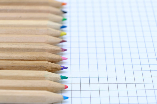 Крупним планом набір барвистих олівців на картатому паперовому аркуші ноутбука для малюнка. Повернутися до концепції школи. Копіювати простір, без людей. Невелика глибина різкості
 - Фото, зображення