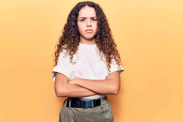 Beautiful kid girl with curly hair wearing casual clothes skeptic and nervous, disapproving expression on face with crossed arms. negative person.  - Foto, Imagen