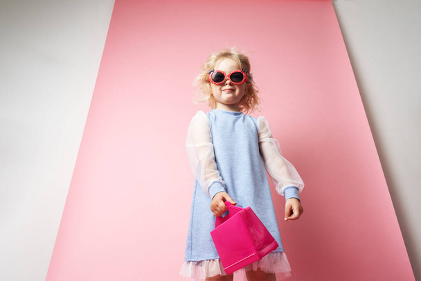 Little girl child in sunglasses with a pink redicle. - Foto, afbeelding
