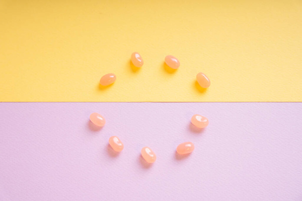 Süße Süßigkeiten in Kreisform auf violettem und gelbem Hintergrund. Ansicht von oben. - Foto, Bild