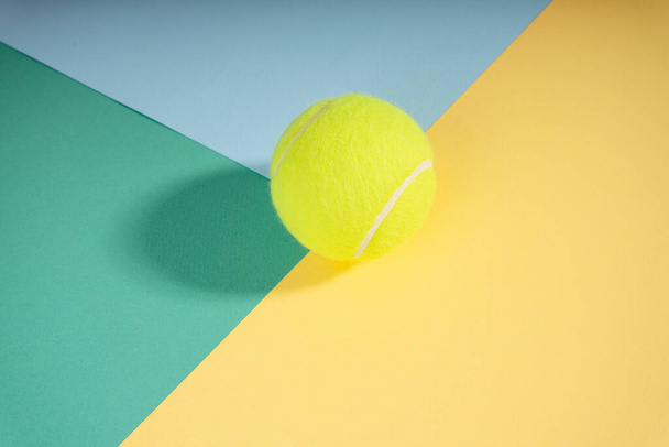 Top view - tennis ball on green blue yellow court paper. Sport concept. - Foto, afbeelding
