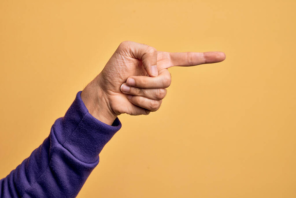 Mão de jovem caucasiano mostrando dedos sobre fundo amarelo isolado apontando com o dedo indicador para o lado, sugerindo e selecionando uma escolha - Foto, Imagem