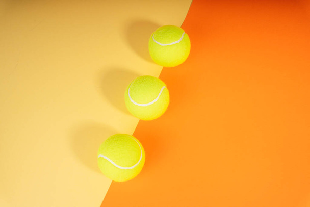 Drei Tennisbälle über den orangefarbenen und gelben Platz. Ansicht von oben. Flache Lage. - Foto, Bild
