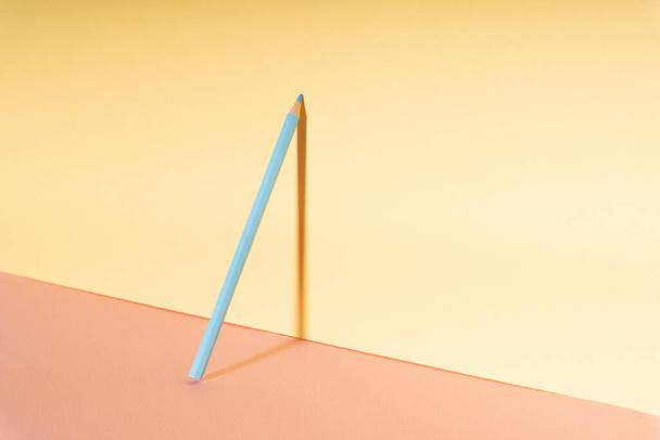 Una matita di colore blu appoggiata da sola sulla parete gialla. - Foto, immagini