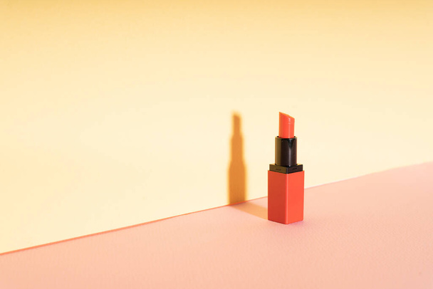A red lipstick bottle at yellow wall. - Fotoğraf, Görsel