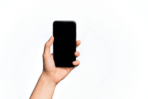 Hand of caucasian young man holding smartphone showing screen over isolated white background - Foto, imagen