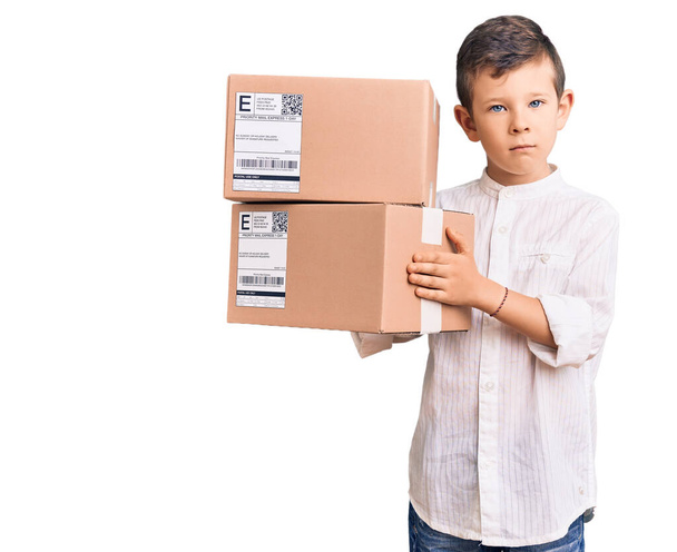 Cute blond kid holding delivery package thinking attitude and sober expression looking self confident  - Photo, Image