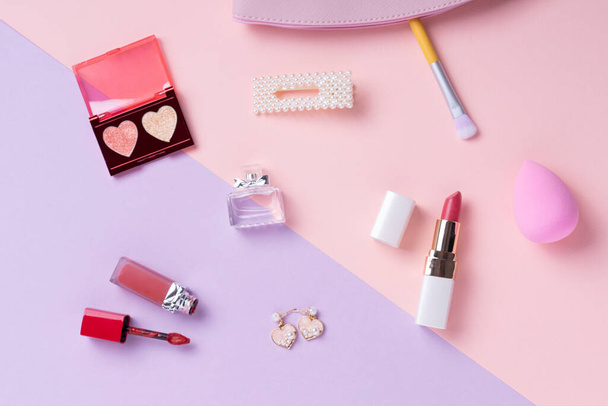 Kozmetikumok top kilátás pasztell rózsaszín és lila asztal. Munkahelyi és kozmetikai zsák. - Fotó, kép