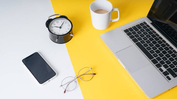 Hintergrund - Gelber Arbeitstisch für Geschäftsleute im modernen Büro, Smartphone, Uhr, Brille, Laptop. - Foto, Bild