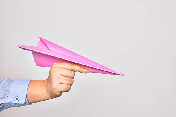 Hand of caucasian young woman holding paper airplane over isolated white background - Photo, Image