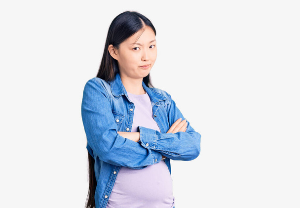 Genç, güzel Çinli kadın hamile, bebek şüphecisi ve gergin kollarını kavuşturarak yüzünde onaylamayan bir ifade bekliyor. negatif kişi.  - Fotoğraf, Görsel