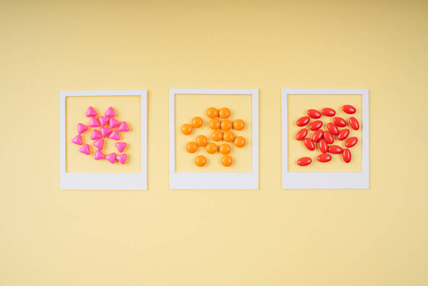 Pilules colorées dans un cadre blanc sur fond jaune. - Photo, image