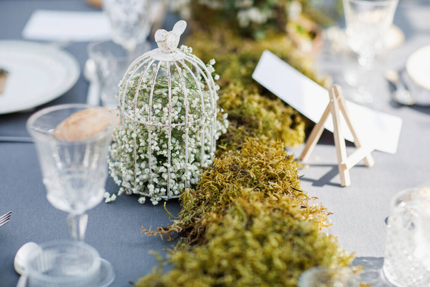 esküvő asztal díszített tányérok, kések és villák, gyertya, moha és zöldség - Fotó, kép