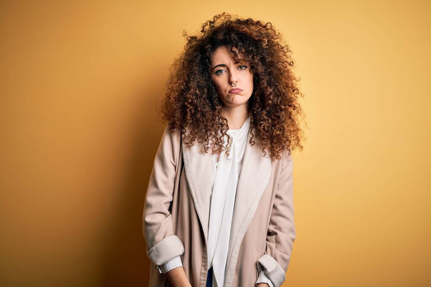 Young beautiful brunette woman with curly hair and piercing wearing casual t-shirt and diadem depressed and worry for distress, crying angry and afraid. Sad expression. - Foto, afbeelding