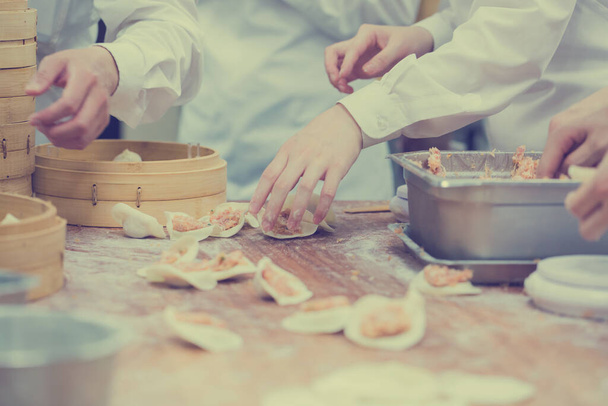 Chefs are cooking Chinese dumplings by the traditional bamboo steamers in a restaurant. Dim Sum chefs working wrapping dumplings at famous restaurant in Taiwan. - Photo, image