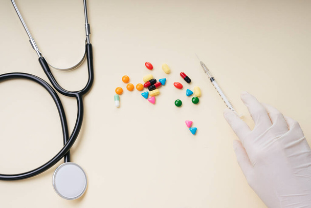 Top view - Lékař v plastových rukavicích s injekční stříkačkou a léky pilulky také stetoskop. - Fotografie, Obrázek