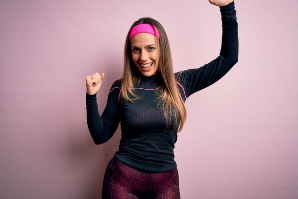 Fiatal szőke fitness nő visel sport edzés ruhák felett elszigetelt háttér Tánc boldog és vidám, mosolygós mozgó alkalmi és magabiztos zenét hallgatni - Fotó, kép