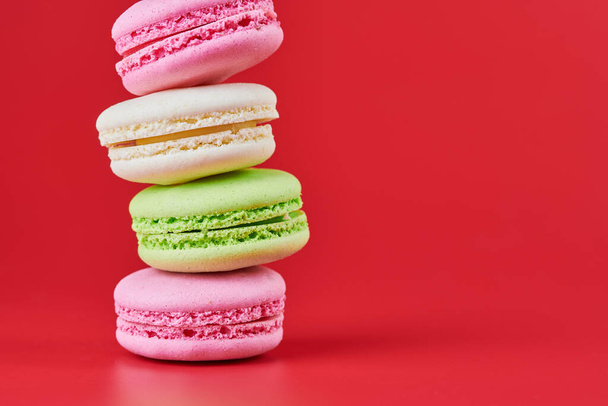 Macaroons on red background. Colorful small cookie from ground almonds and coconut. Popular confectionery. Tasty snack food for take away, copy space - Photo, Image