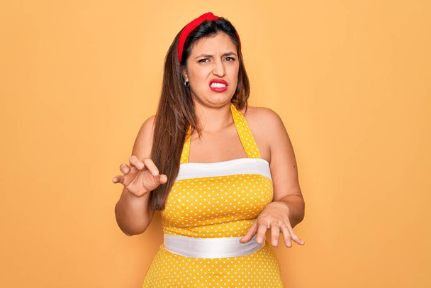 Nuori latino pin up nainen yllään muoti seksikäs 50s tyyli yli keltainen tausta vastenmielinen ilme, tyytymätön ja pelokas tekee inhoa kasvot, koska vastenmielisyys reaktio. - Valokuva, kuva